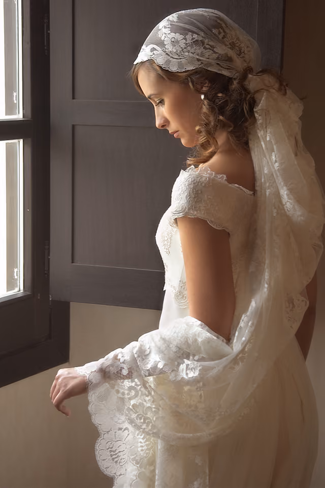 Novia con mantilla junto a una ventana